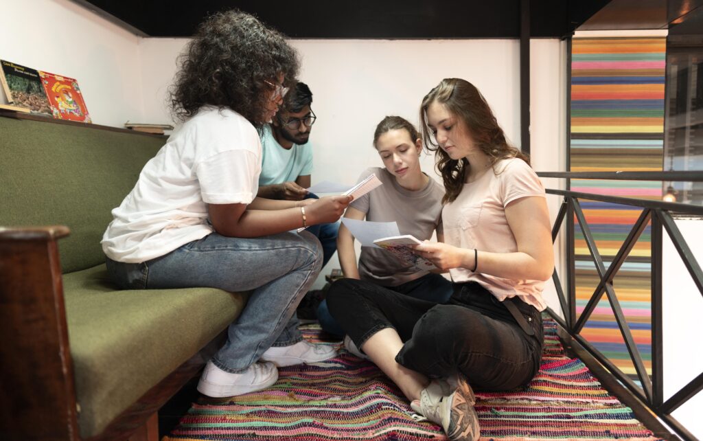 LGBTQ+ friends discussing and sharing reading materials in a supportive group setting.