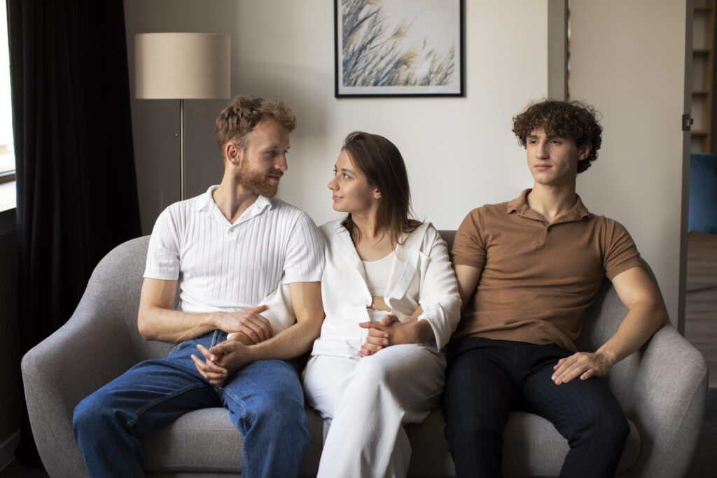 Three people sitting together and holding hands during a supportive conversation