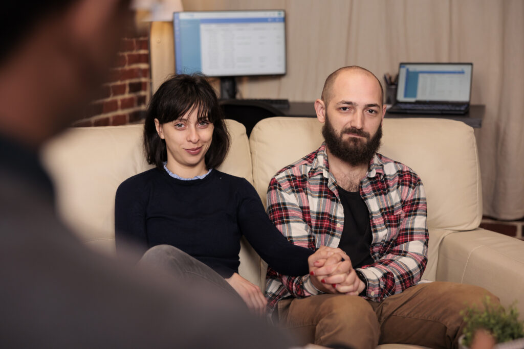 Couple holding hands during a couples therapy session with a therapist.