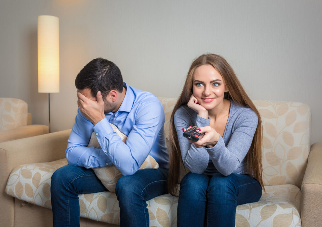 Couple experiencing relationship tension while watching television together.